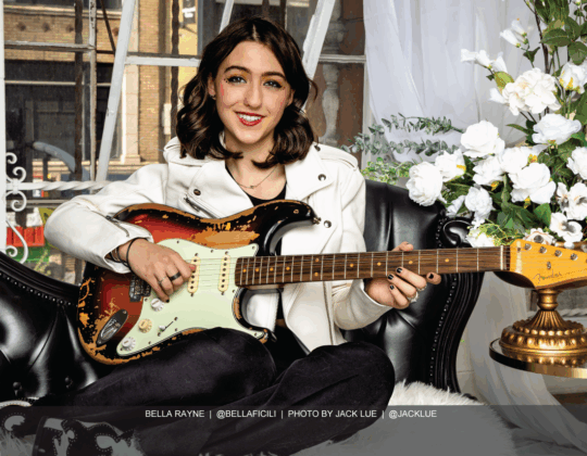 Bella Rayne featured in the April 2025 Guitar Girl Magazine calendar playing a Fender electric guitar