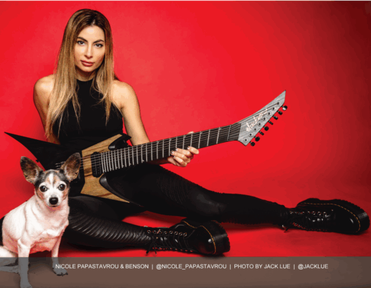 Nicole Papastavrou featured in the July 2025 Guitar Girl Magazine calendar holding an electric guitar with her dog Benson