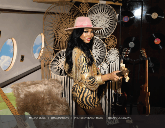 Malina Moye featured in the November 2025 Guitar Girl Magazine calendar holding an electric guitar in a styled studio setting