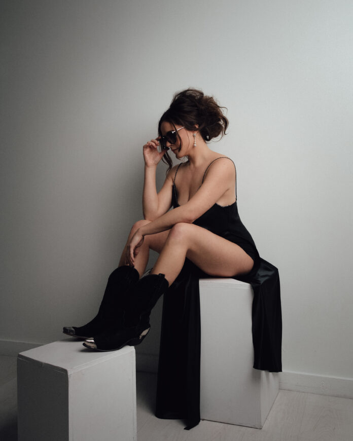 woman wearing sunglasses in black dress and cowboy boots