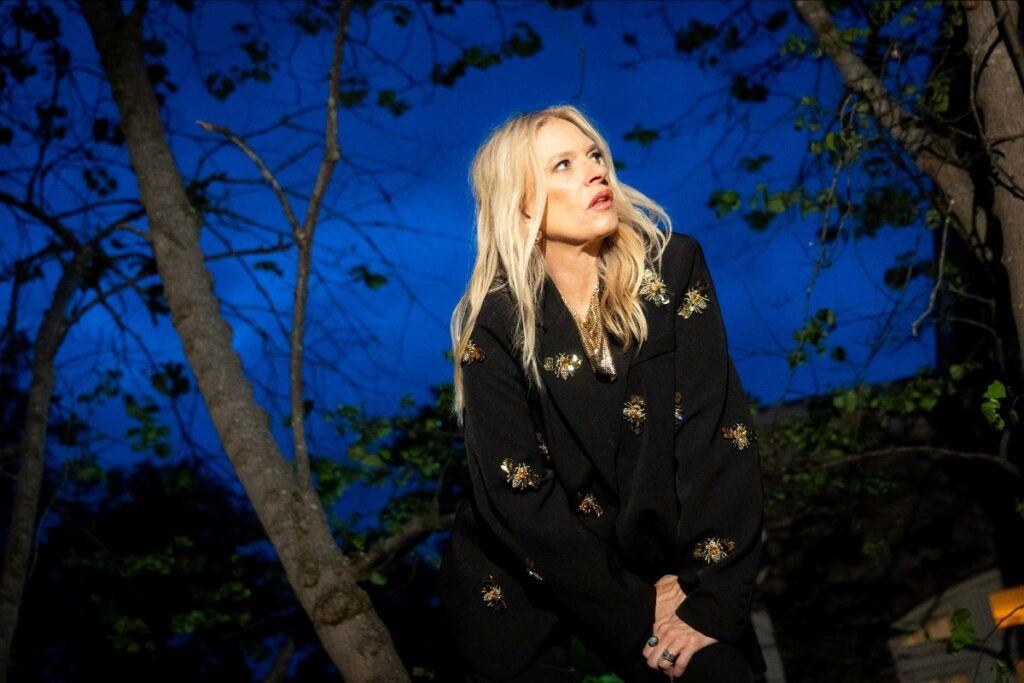 blonde woman at night posing between two trees gazing