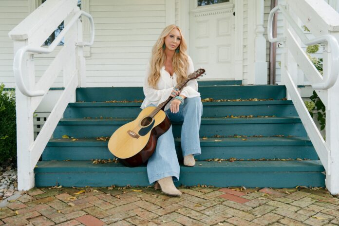 Becca Bowen posing with her acoustic guitar to promote her new single “Mama’s Prayer.”