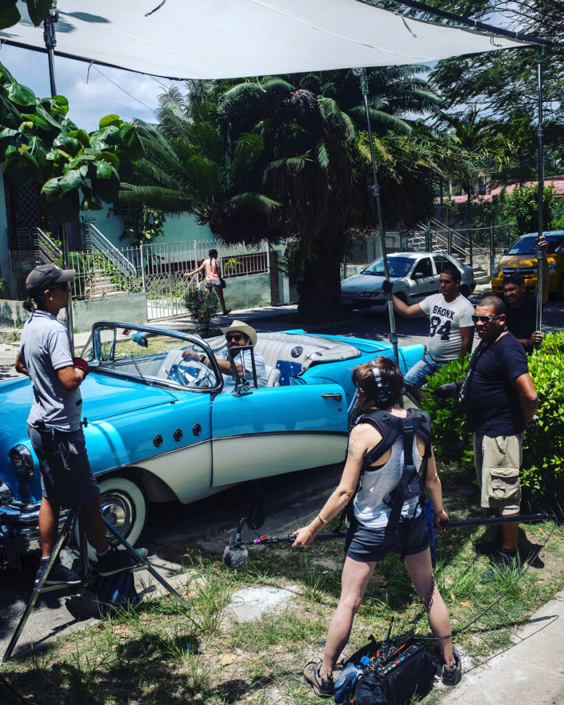 Behind the scenes with Hannah Fairlight recording sound on a film set with a classic blue convertible