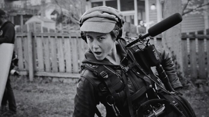 Black-and-white portrait of Hannah Fairlight working on location with boom mic and audio equipment