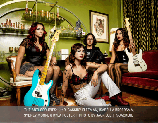 August page of the 2026 Guitar Girl Magazine calendar featuring The Anti Groupies, a female-led band posing with guitars and bass in a vintage lounge setting.