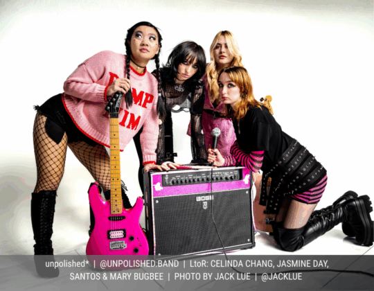 December page of the 2026 Guitar Girl Magazine calendar featuring the band unpolished* posing with guitars, microphone, and amplifier against a white studio backdrop.