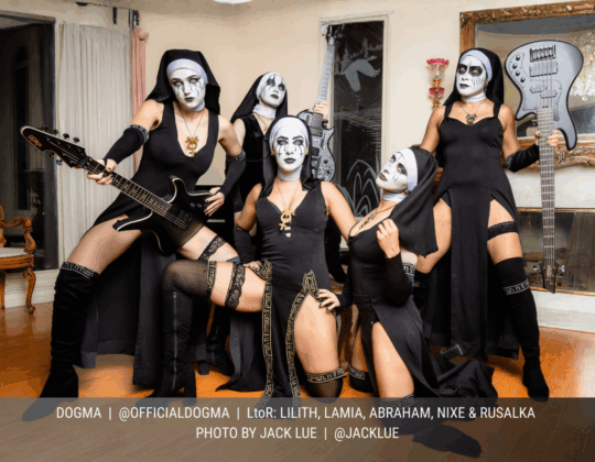 October page of the 2026 Guitar Girl Magazine calendar featuring the band DOGMA posing in theatrical nun-inspired costumes while holding electric guitars.