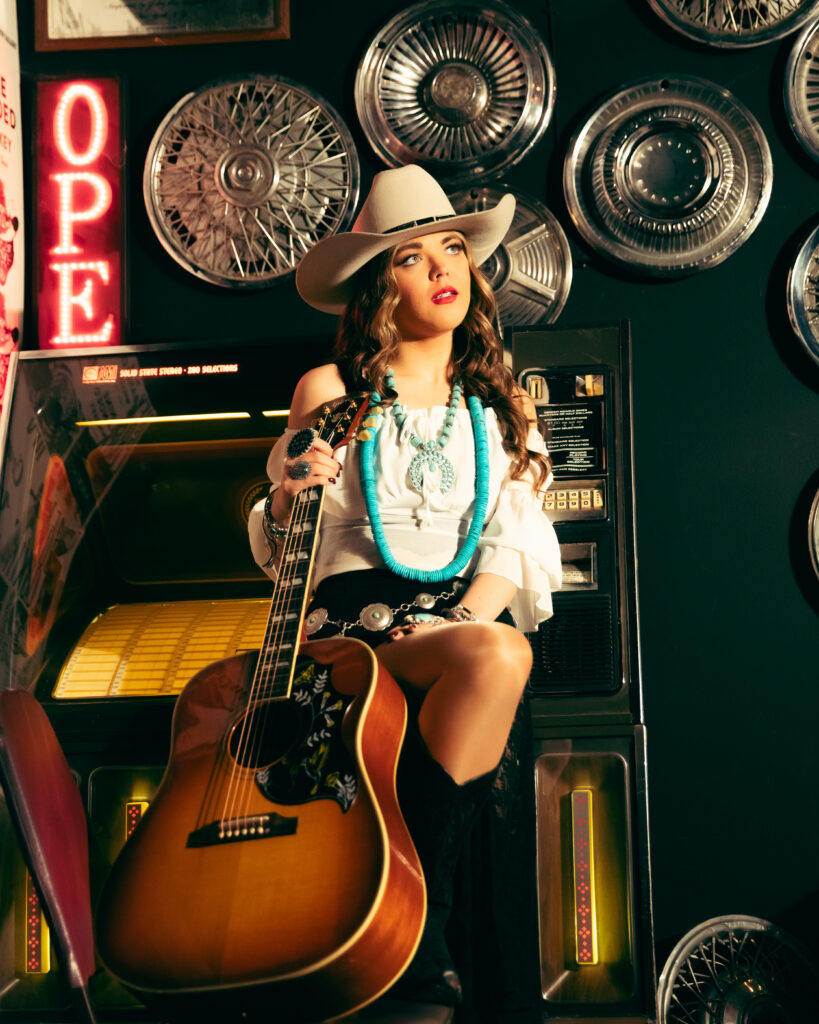 Female country artist Bella Lam in retro jukebox setting with Gibson guitar