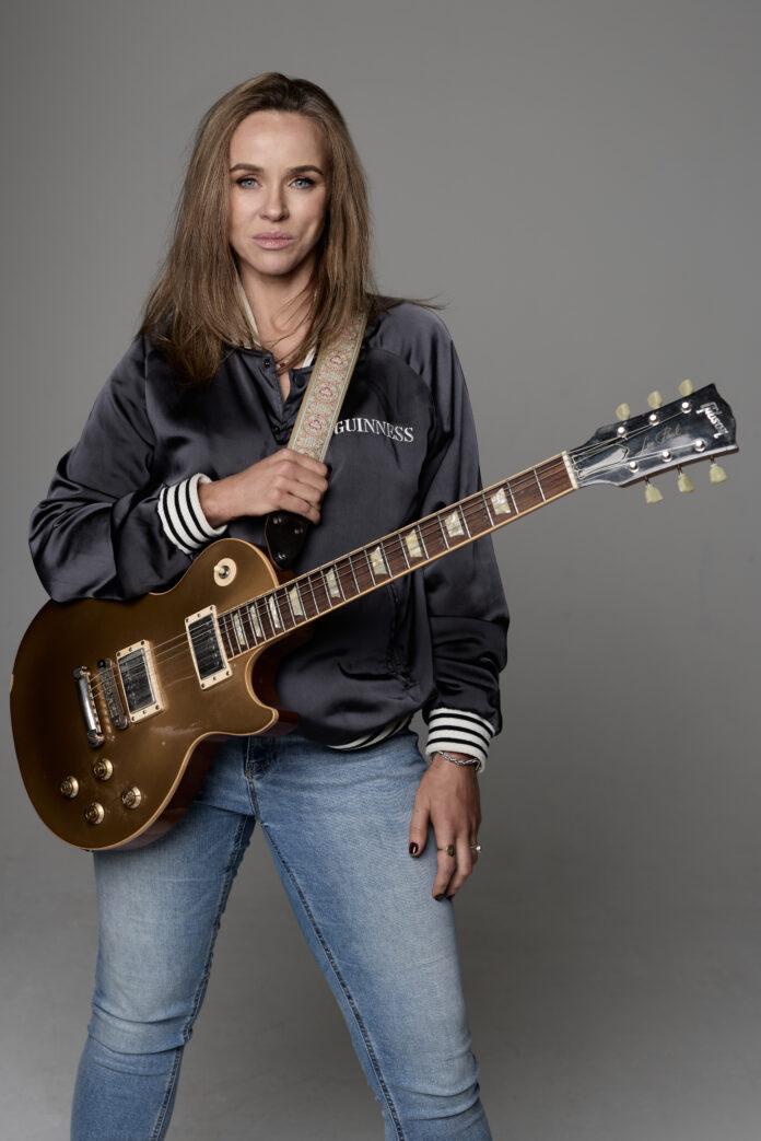 Gráinne Duffy holding a Gibson Les Paul guitar promoting her album What Am I Supposed To Do