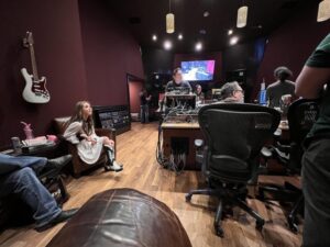 Bella Lam seated in the control room with musicians and studio personnel during a “Bootfirst” session at Blackbird Studio.