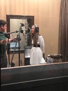 Bella Lam wearing headphones at a studio microphone while working with producer Lowell Reynolds at Blackbird Studio.